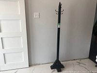 Full view of the black wood coat tree showing its triangular base and height.