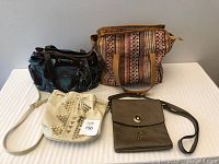 Four purses on a white surface showing two views with straps placed differently.