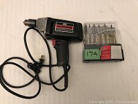 Craftsman 3/8 reversible drill with power cord and a set of drill bits in plastic case