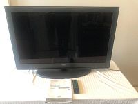 Front view of Seiki 40-inch LCD television on oval stand with remote and manual in front.