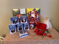 Photo showing the whole lot of Christmas items arranged on a table including boxed ornaments, tins, angel figure, and ornaments.