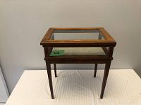 Front view of the wooden display table with glass top in closed position, showing the overall shape and finish.