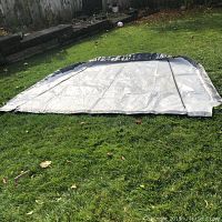 Photo showing the large tarp laid flat on grass, highlighting dimensions and grey edging.