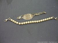 Two bracelets displayed on a dark surface. One bracelet is a pearl-style beaded bracelet and the other is a chain bracelet with a Medic Alert identifier plate.