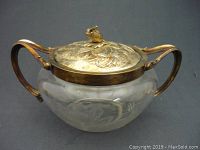 Side angle view showing clear etched glass body and silver plated handles and detailed lid with finial.