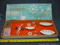 Full box with orange interior tray showing all fitting parts and packaging lid with ship wheel design.