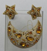 Front view of crescent moon gold-tone brooch with amber crystal rhinestones, showing intricate gold filigree detailing and varying shapes of crystals.