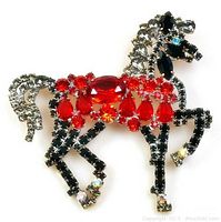Close-up image of the Large Vintage Lilien Czech prancing show horse brooch featuring red, black, clear, and blue glass rhinestones in prong settings.