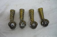 Four vintage metal claw feet holding round marbles, laid flat showing top and claw details.
