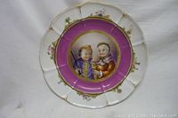 Front view of antique hand-painted porcelain cabinet plate with children portrait and floral scalloped rim