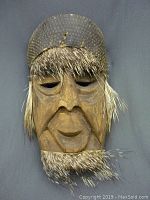 Full view of the vintage African-style wooden mask with natural hair accents around the forehead, eyebrows, and chin, showing the overall shape and condition.