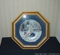 Full view of Keirstead collectors plate with winter scene mounted in hexagon gold embossed frame.