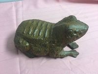 Side view of cast iron frog doorstop showing textured surface and detailed frog features.