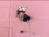 Full view of the cast metal dog dinner bell on a pink surface showing the dog above the bell and pull string.