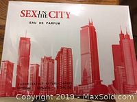 Photo of the front side of the sealed box showing the branding 'Sex in the City Eau de Parfum' with a red city skyline graphic.