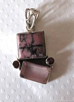 Front view of sterling silver pendant showing square rhodonite, rectangular rose quartz, and two small round garnet stones with open work bail