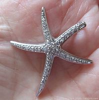 Top-down view of starfish-shaped sterling silver pendant showing the cubic zirconia stones embedded on each arm.
