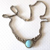Full view of the silver chain with round blue larimar pendant and lobster claw clasp on a dotted background.