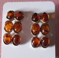 Front view of the pair of sterling silver amber earrings showing six oval amber stones on each earring in a 2 by 3 arrangement.