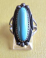 Top view showing elongated oval turquoise stone bezel set in sterling silver with decorative stamped and beaded silverwork.