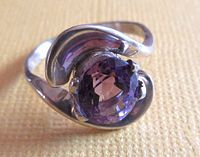 Front view of vintage sterling silver ring with oval lab-created alexandrite stone showing faceted purple gemstone and swirl silver design.