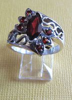 Front angled view showing full ring design with marquise-shaped red center stone and smaller side stones, and open work sterling silver band.
