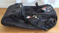 Top and side view of black canvas American Tourister bag showing main zipper, handles, shoulder strap attachment and lock.
