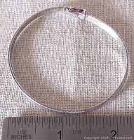 Sterling silver bracelet laying flat beside a ruler showing length approximately 7 inches.