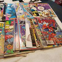 Top view of a large assortment of comic books stacked, showcasing covers from Spider-Man, Gen13, and other series.