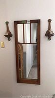 Wall hung wooden framed mirror with four-paneled glass and minor scratches on frame with wooden angel sconces on sides