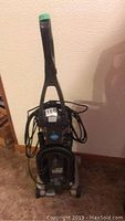 Full view of upright Hoover Vacuum cleaner showing handle, power cord coiled behind, and base with hose attachment.