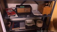Photo of shelving with all items visible including vintage radio, shoe shine kit, ceramic tiles, planter, drywall tape, dictionary