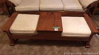 Front view showing wooden table with two built-in seats with white upholstery cushions, minor stains visible