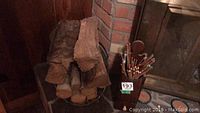 Photo showing stacked firewood logs in a metal holder next to a fireplace with the match holder full of long colored-tip matches and the poker visible.