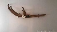 Overall view of the wooden wall art mounted on the wall showing the full length and attached flowers.