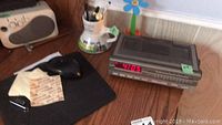 Sharp adding machine keyboard, Citizen clock radio, pens in mug, black mouse and mouse pad on wooden desk