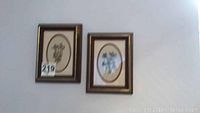 Two framed floral prints with oval matting showing floral illustrations, smaller size.