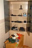 D-Link home network equipment, satellite finder, cameras, and Mastercraft laser on shelves with power bars and cables below.