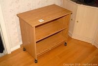 Wooden portable cabinet with two shelves and caster wheels, shown from an angled front view