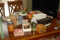 Overview of lot items including wall hanging, ice bucket, faux fruit, candles, wooden box, and mirrored tray on table