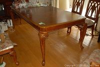Long view of the rectangular wooden dining table, showing carved legs and surface wear.