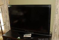 Front view of Toshiba 55" TV on stand with remote placed on shelf.