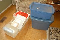 Photo showing all storage bins including two stacked blue Rubbermaid lidded bins and multiple plastic bins without lids in white and red.