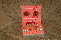 Full view of Meng Liang miniature metal dish kit in original box with red fabric lining showing two pairs of chopsticks on circular holders, plates, bowls, goblets and horn-shaped decorative items