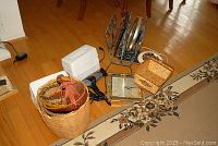 Wide view showing metal magazine rack, clocks, hair blow dryers, baskets and tissue box covers arranged on floor.