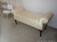 Full view of the floral patterned upholstered bench showing wood legs and rolled arms at each end.
