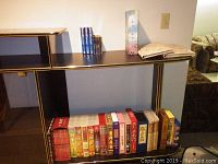 Wide view of black shelf with assorted Asian movie titles in VHS and DVD cases arranged on lower shelf