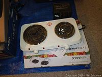 White HomeMax double electric burner with two coil heating elements, placed on top of HomeMax box with the SuperMax mini furnace located behind it.