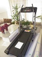 Full front view of the treadmill showing the walking belt, control panel, handrails, and manual on belt.