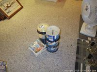 Photo showing stacked spindles of blank CDs including Philips and Verbatim brands along with a bundle of clear plastic CD jewel cases on carpeted floor.